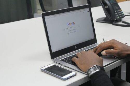 man typing on laptop on table with phone